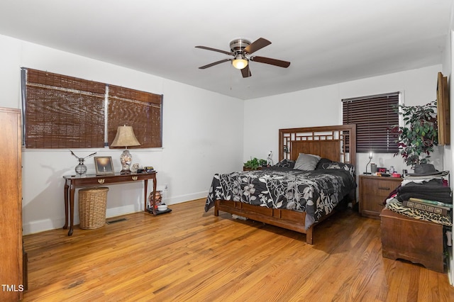 bedroom with a ceiling fan, visible vents, wood finished floors, and baseboards