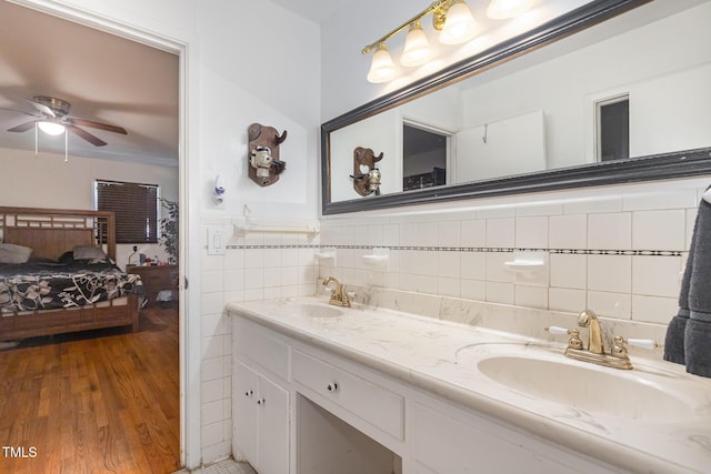 full bath featuring double vanity, ceiling fan, ensuite bath, and a sink