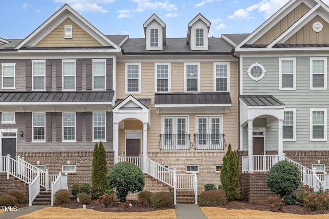 townhome / multi-family property featuring brick siding, stairway, board and batten siding, a standing seam roof, and metal roof