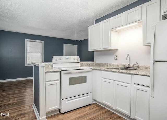 kitchen featuring sink, white cabinets, hardwood / wood-style flooring, kitchen peninsula, and white appliances