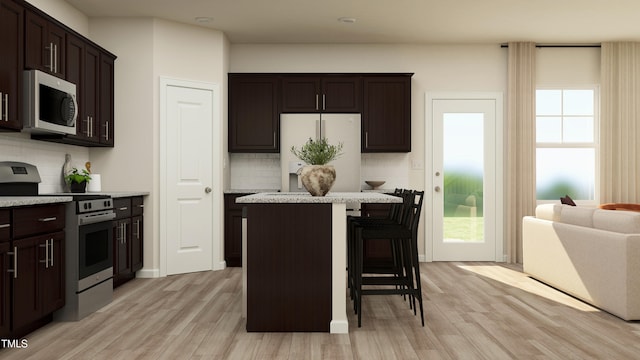 kitchen featuring stainless steel appliances, a kitchen breakfast bar, a center island, and a wealth of natural light