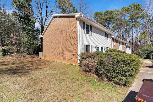 view of home's exterior with a garage, a yard, and brick siding