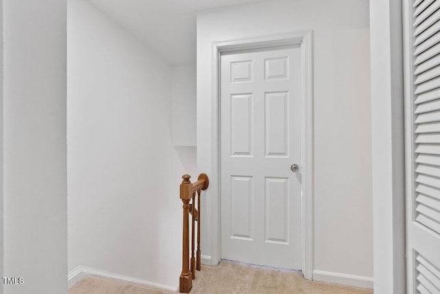 corridor with an upstairs landing, light carpet, and baseboards