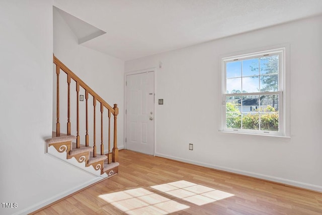 entryway with stairs, wood finished floors, and baseboards