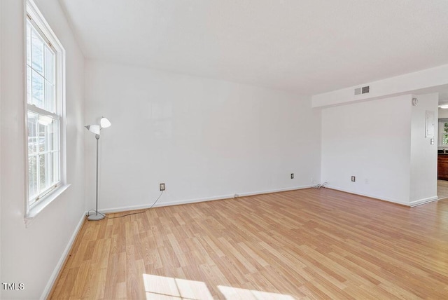 unfurnished room with light wood-type flooring, visible vents, and baseboards