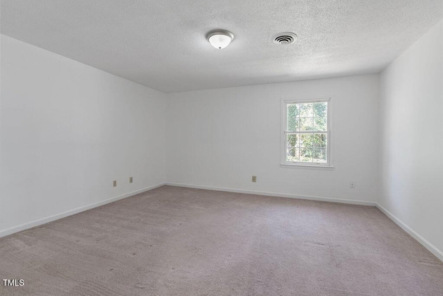 carpeted spare room with baseboards, visible vents, and a textured ceiling