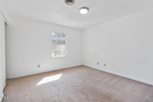 carpeted spare room with visible vents, a textured ceiling, and baseboards