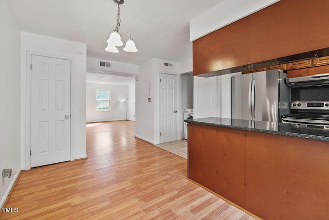 kitchen featuring light wood finished floors, stainless steel appliances, under cabinet range hood, pendant lighting, and a notable chandelier