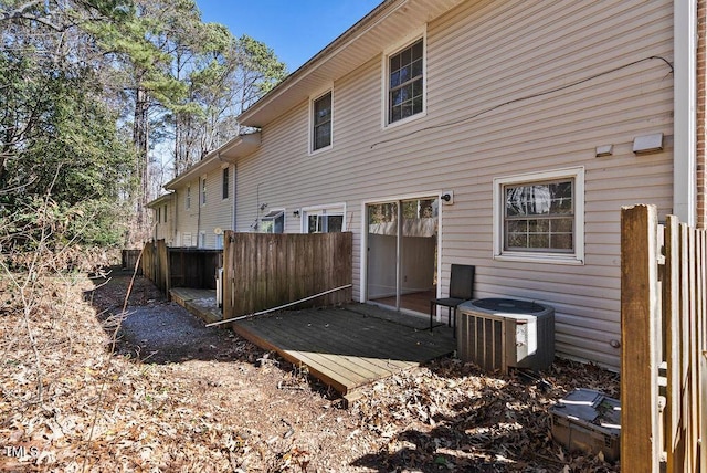 rear view of property with cooling unit, a wooden deck, and fence