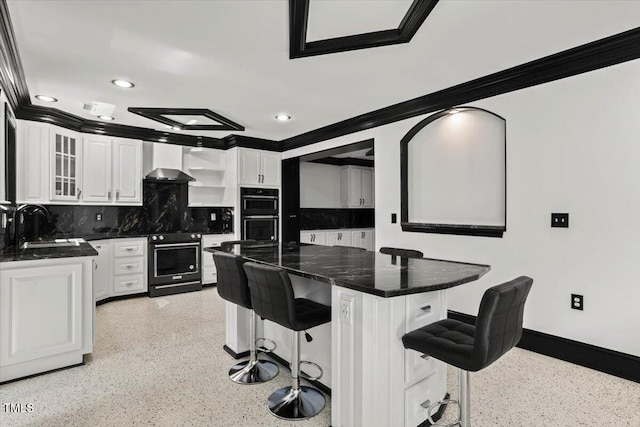 kitchen with wall chimney exhaust hood, sink, a kitchen breakfast bar, white cabinets, and black appliances