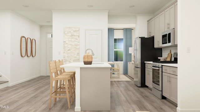 kitchen with ornamental molding, appliances with stainless steel finishes, a kitchen breakfast bar, and light hardwood / wood-style flooring