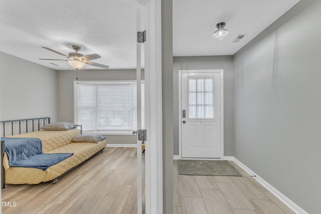 entrance foyer featuring light wood-type flooring, a healthy amount of sunlight, visible vents, and a textured ceiling