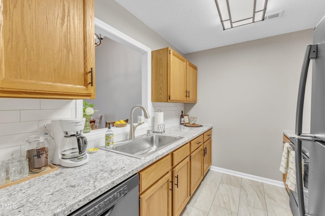 kitchen featuring tasteful backsplash, baseboards, freestanding refrigerator, a textured ceiling, and a sink