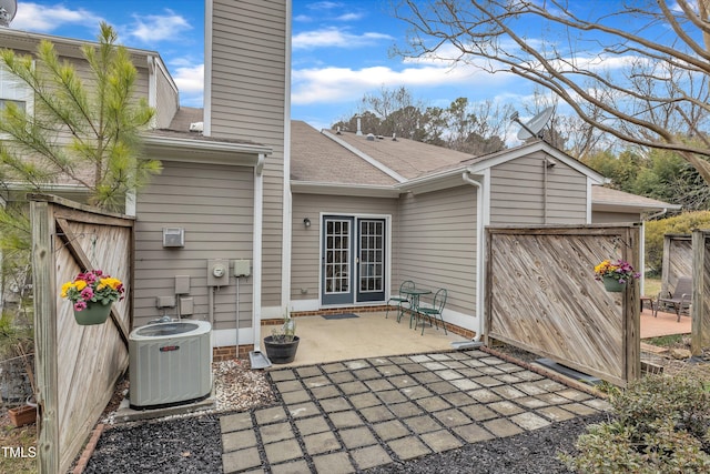 back of property with a patio, central AC unit, an attached garage, fence, and a chimney