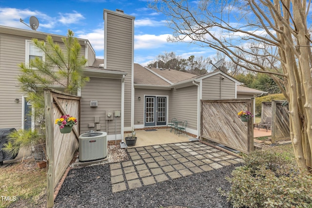 rear view of house featuring a garage, a patio, a chimney, fence, and central air condition unit