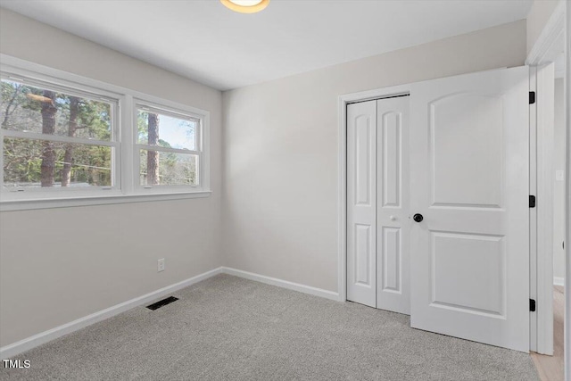 unfurnished bedroom featuring light colored carpet and a closet