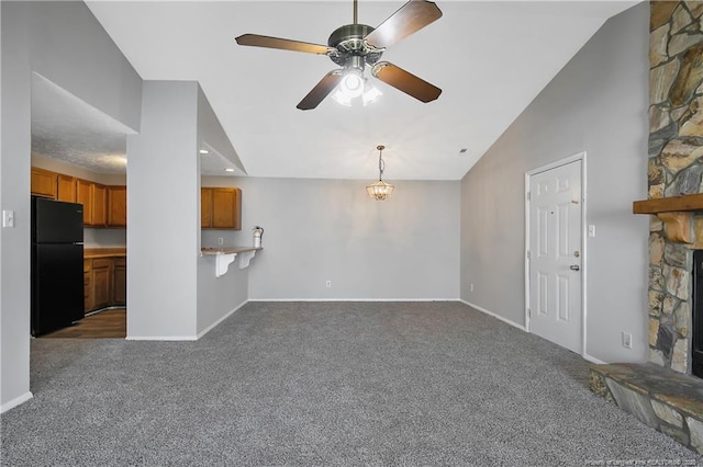 unfurnished living room with ceiling fan, a fireplace, vaulted ceiling, and dark colored carpet