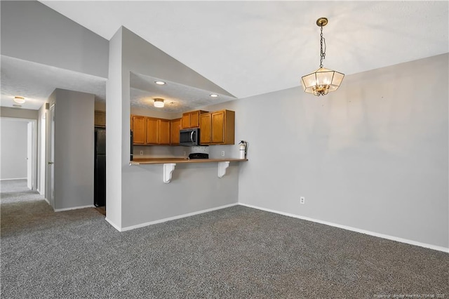 kitchen with a breakfast bar area, decorative light fixtures, vaulted ceiling, carpet flooring, and kitchen peninsula