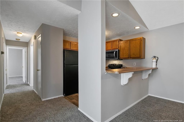 kitchen with a breakfast bar, a textured ceiling, light carpet, kitchen peninsula, and black appliances