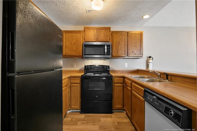 kitchen featuring sink, a textured ceiling, light wood-type flooring, and black appliances