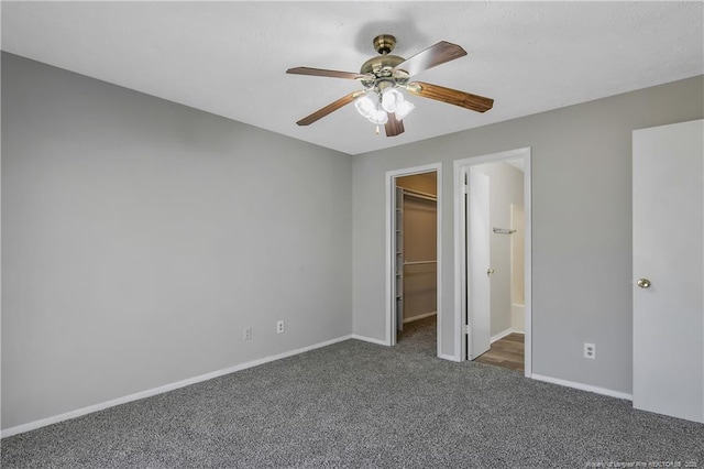 unfurnished bedroom featuring ceiling fan, a walk in closet, a closet, and dark colored carpet