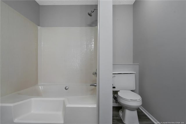 bathroom featuring hardwood / wood-style flooring, tub / shower combination, a textured ceiling, and toilet