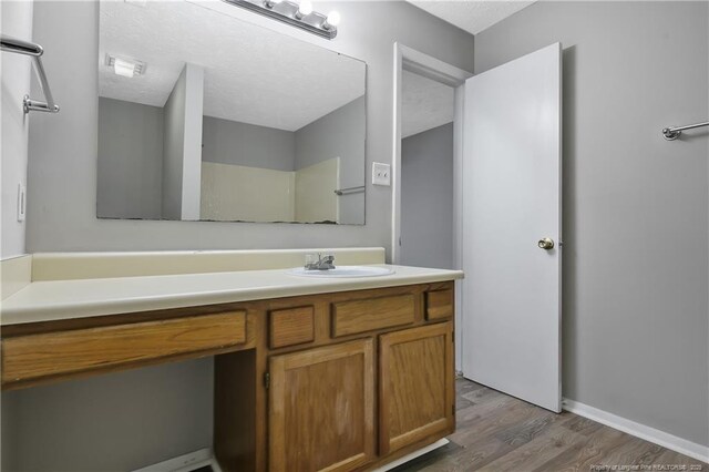 bathroom featuring hardwood / wood-style flooring, vanity, and a textured ceiling