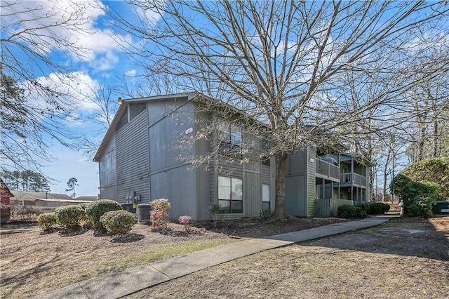 view of side of home with central AC and a balcony