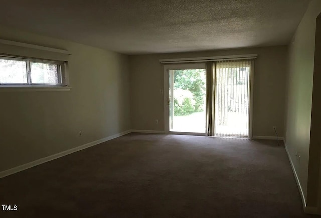 unfurnished room with carpet, baseboards, and a textured ceiling