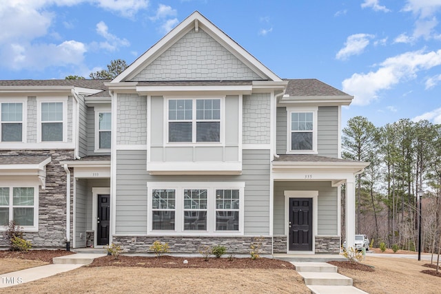 view of front of property featuring stone siding and a shingled roof