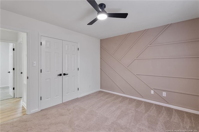 unfurnished bedroom featuring ceiling fan, a closet, and light carpet