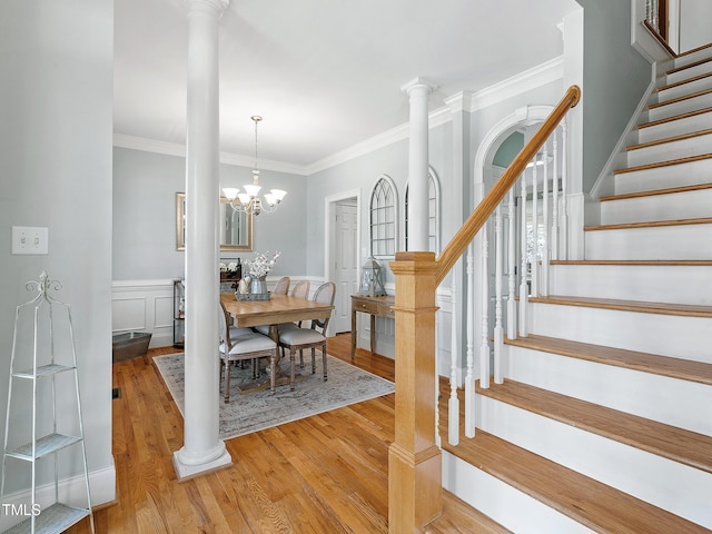 dining space with ornate columns, light wood-style flooring, stairs, and ornamental molding