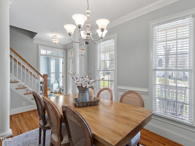 dining room featuring light wood-style floors, crown molding, an inviting chandelier, and stairs