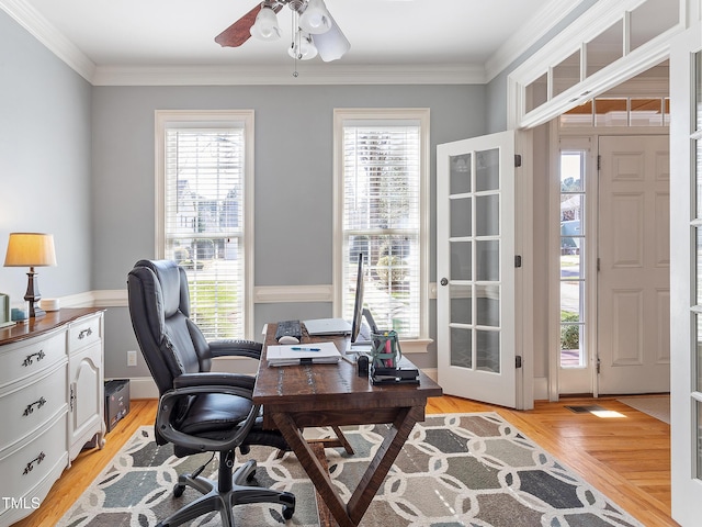 home office featuring a healthy amount of sunlight, light wood-style floors, and ornamental molding