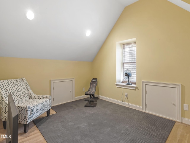 living area with baseboards, vaulted ceiling, and wood finished floors