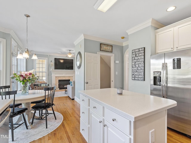 kitchen with a center island, crown molding, stainless steel appliances, light wood-style flooring, and a glass covered fireplace