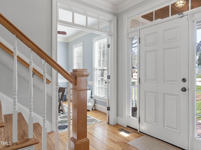 foyer with ornamental molding, stairway, light wood-style flooring, and baseboards