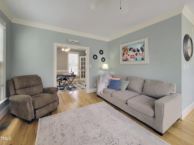 living room with light wood-type flooring, ceiling fan, baseboards, and crown molding