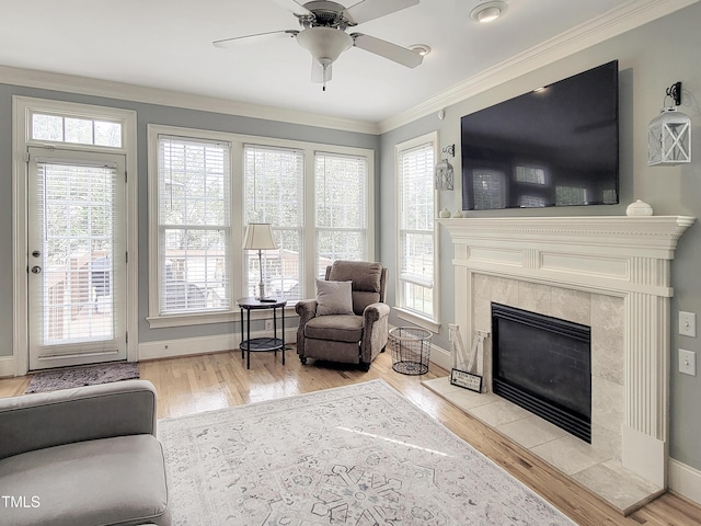 living room featuring baseboards, ceiling fan, ornamental molding, wood finished floors, and a fireplace