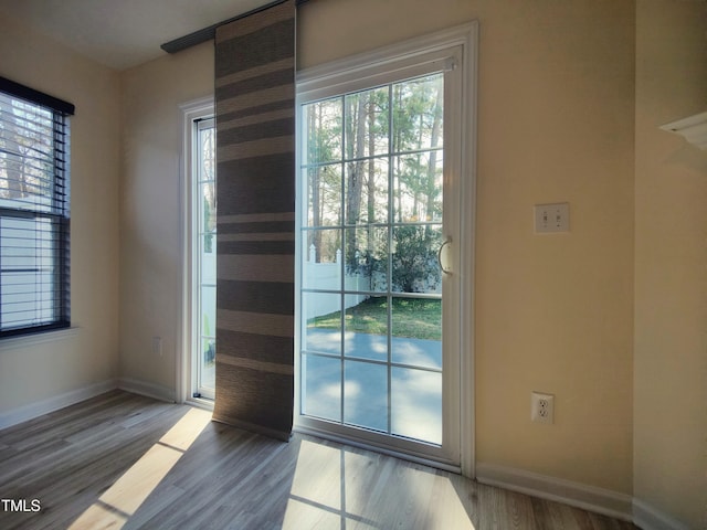 doorway with wood finished floors and baseboards