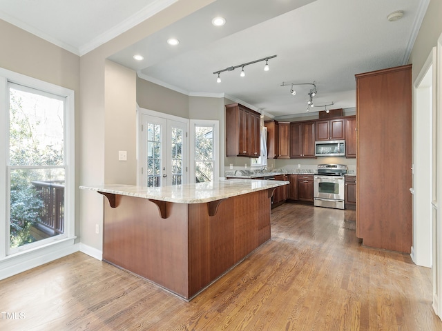725 Littleleaf Ct, Holly Springs, NC 27540 - kitchen featuring wood finished floors, a peninsula, stainless steel appliances, and ornamental molding