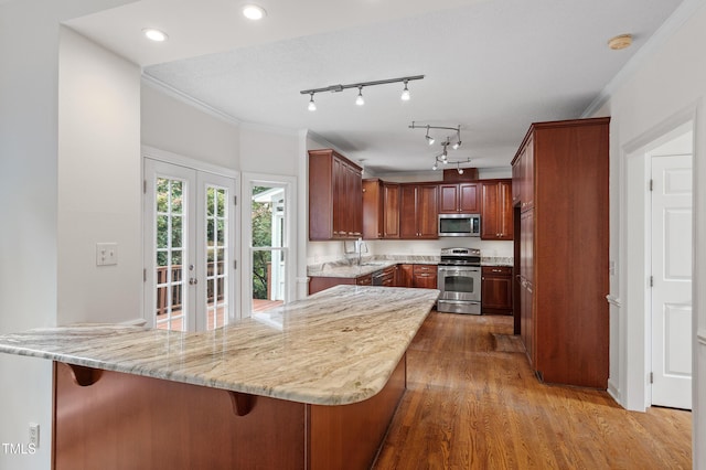 725 Littleleaf Ct, Holly Springs, NC 27540 - kitchen with appliances with stainless steel finishes, wood finished floors, light stone counters, ornamental molding, and recessed lighting