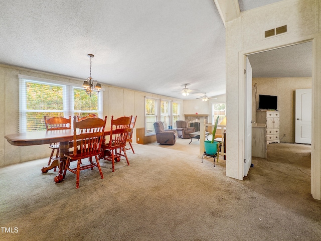 dining space with ceiling fan with notable chandelier, carpet flooring, and a textured ceiling