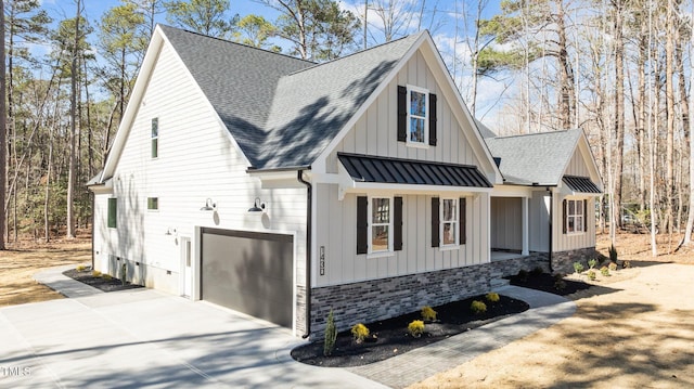 view of home's exterior featuring metal roof, a shingled roof, concrete driveway, board and batten siding, and a standing seam roof