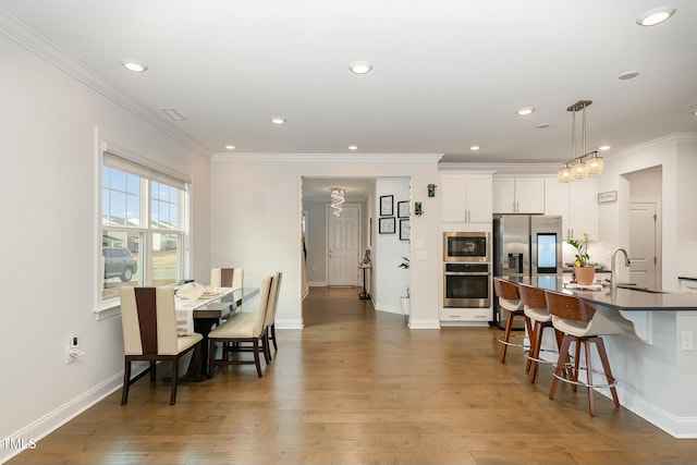 dining space with sink, crown molding, and dark hardwood / wood-style floors