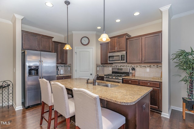 kitchen featuring a kitchen island with sink, hanging light fixtures, dark brown cabinets, and appliances with stainless steel finishes