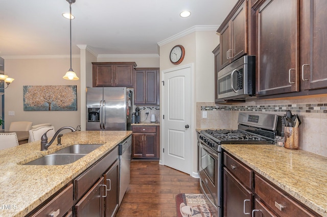 kitchen with appliances with stainless steel finishes, decorative light fixtures, sink, dark hardwood / wood-style flooring, and light stone countertops