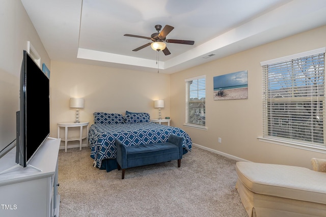 carpeted bedroom featuring a raised ceiling and ceiling fan