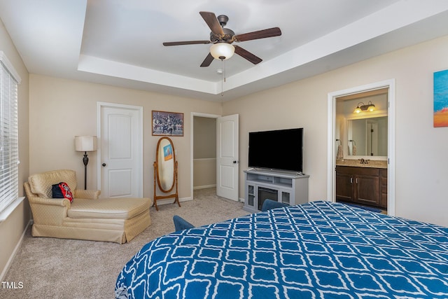 carpeted bedroom with sink, a raised ceiling, ceiling fan, and ensuite bathroom