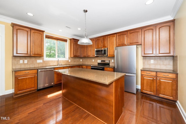532 Front Ridge Dr, Cary, NC 27519 - kitchen with stainless steel appliances, dark wood-type flooring, a center island, brown cabinets, and ornamental molding